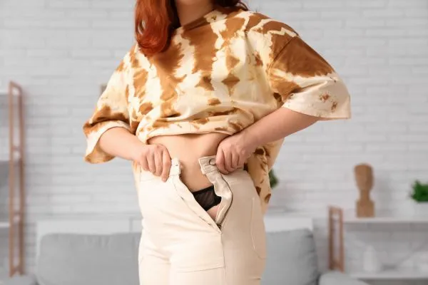 Image of woman trying to do her trousers up after pregnancy weight gain Herefordshire