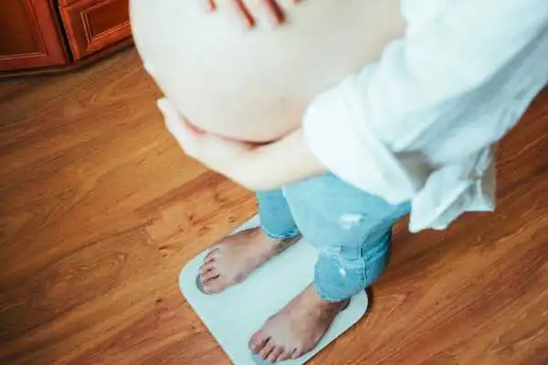 Image of woman weighing herself and experiencing weight gain through pregnancy Herefordshire
